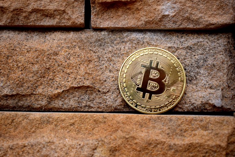 bitcoin token near a brick wall