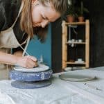white woman painting on clay