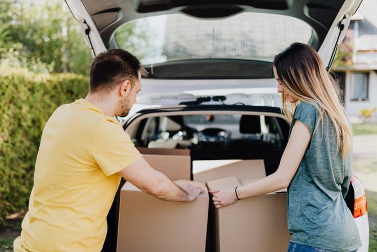 couple putting away boxes in new financed car